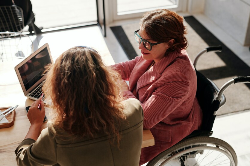 Disabled CPA reading an industry news letter with a friend